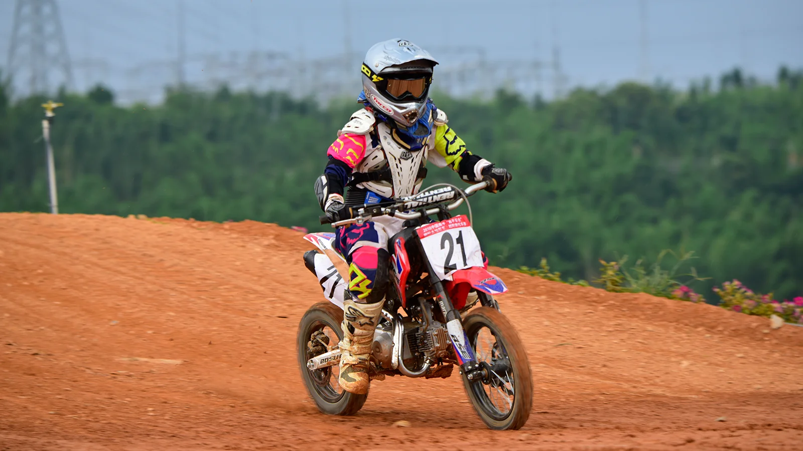 Rider on a small dirt bike on a red clay track